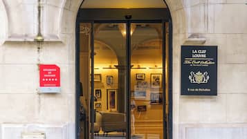 The entrance to La Clez Louver, a hotel with a classic stone facade and a glass door entrance.