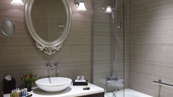 Un baño moderno con un espejo ovalado grande, un lavamanos blanco y una ducha con cerramiento de vidrio.