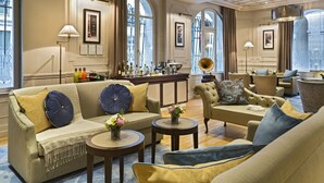 Ein großzügiger Lounge-Bereich mit einer Couch, Sesseln und einem Couchtisch, mit großen Fenstern und stilvoller Einrichtung.
