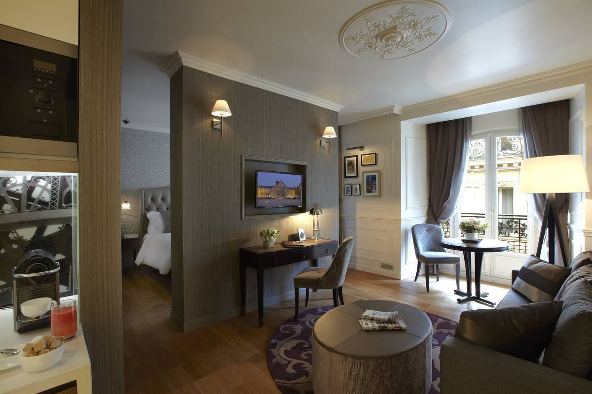 Ein modernes Hotelzimmer mit Fernseher, Schreibtisch und Sitzecke.