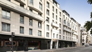 Un hotel a più piani con facciata moderna, ampie finestre e un ingresso a livello strada con un negozio ben visibile.
