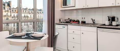 A modern kitchen with white cabinets, a microwave, and a dining area with a table set for two.