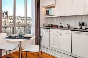 Una cucina moderna con mobili bianchi, un forno a microonde e un'area pranzo con un tavolo apparecchiato per due persone.