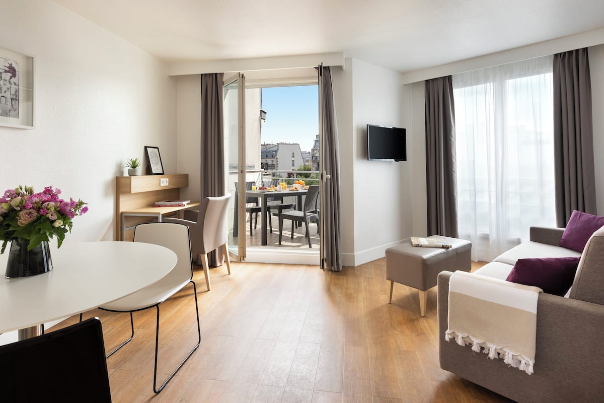 Una habitación de hotel moderna con comedor, sofá y televisor.