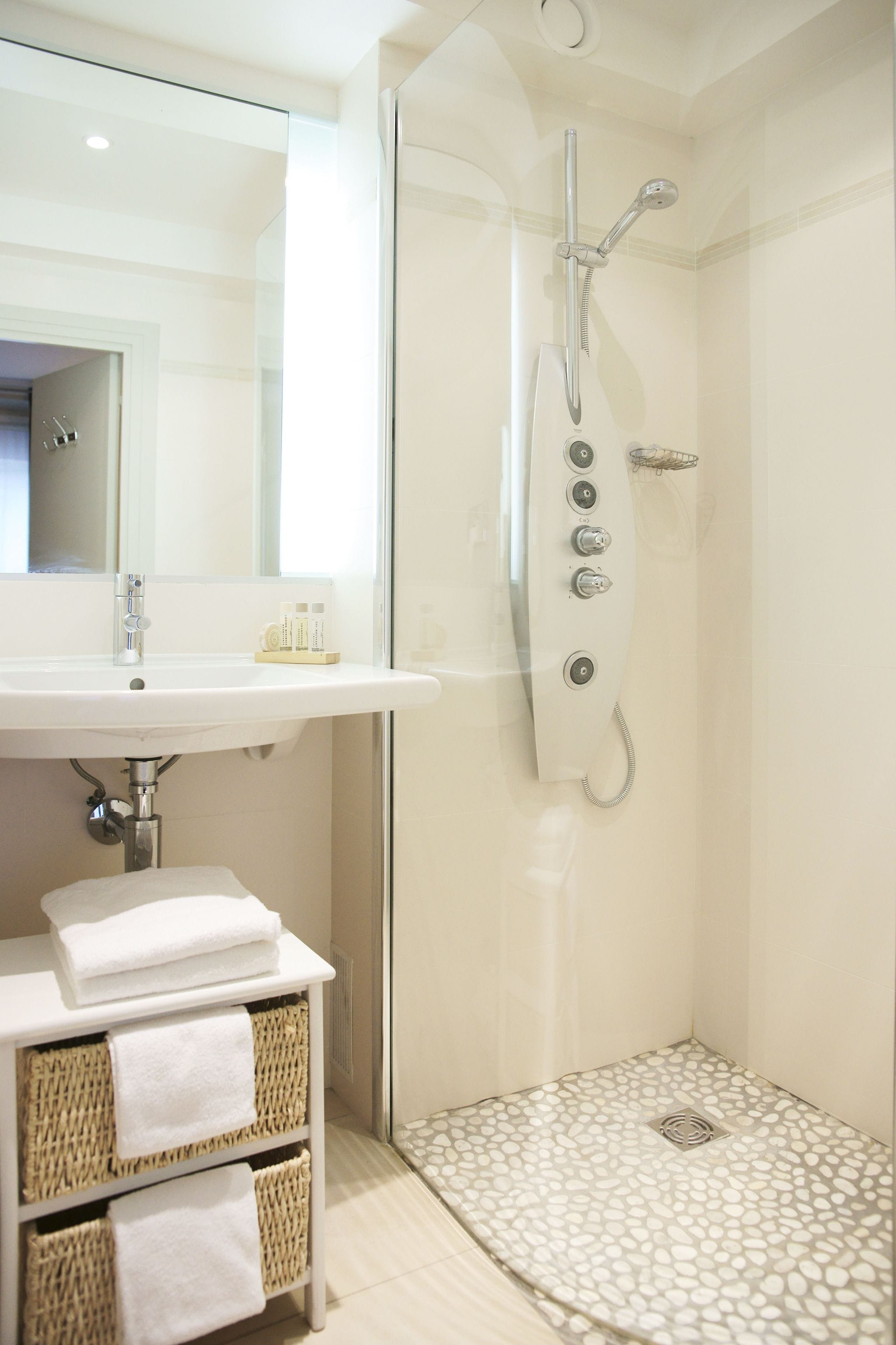 Un baño moderno con ducha de vidrio, lavamanos blanco y un perchero para toallas.