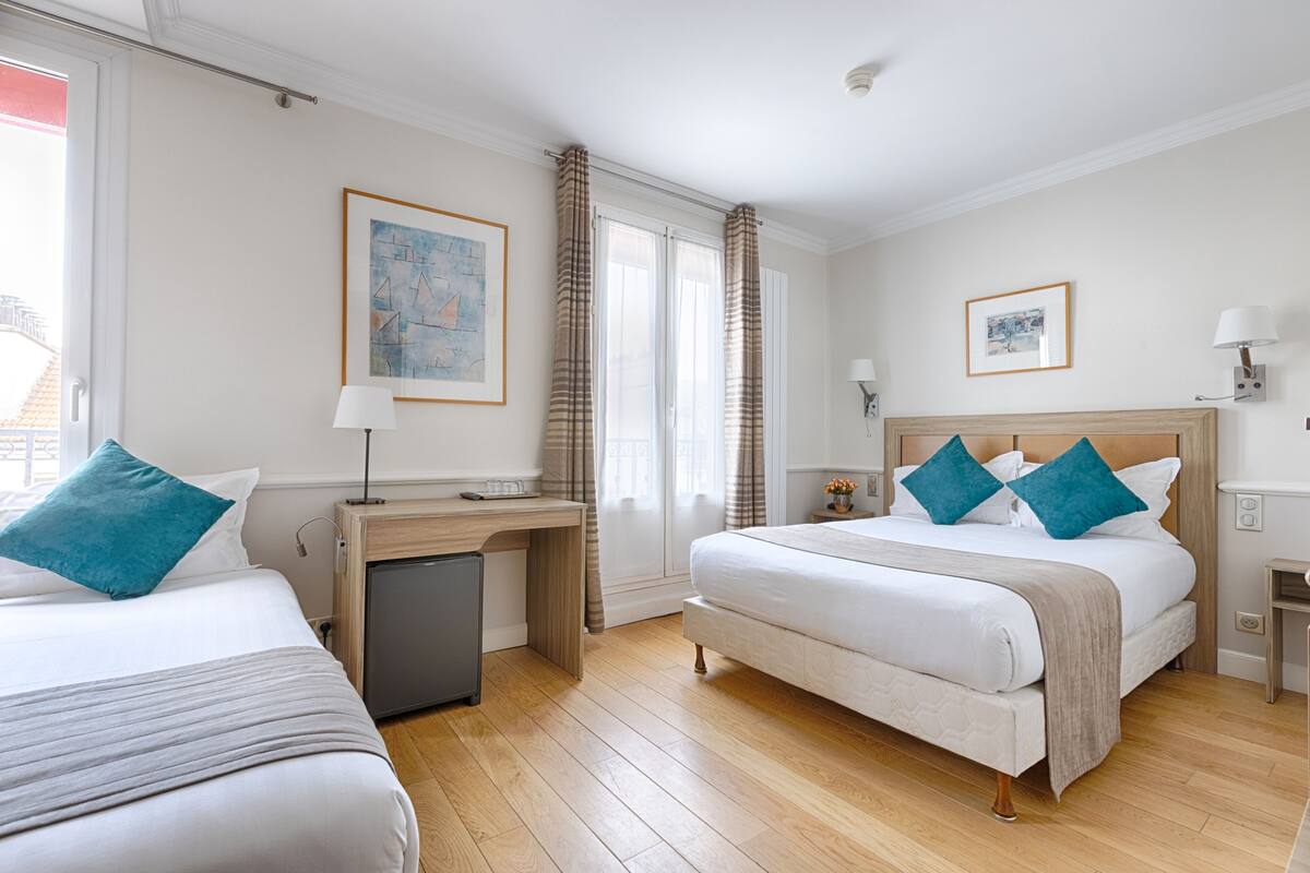 Ett hotellrum med två sängar, ett skrivbord och ett litet skåp.