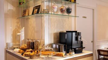 Una barra de desayuno con diferentes alimentos, una máquina de café y frascos de vidrio decorativos.