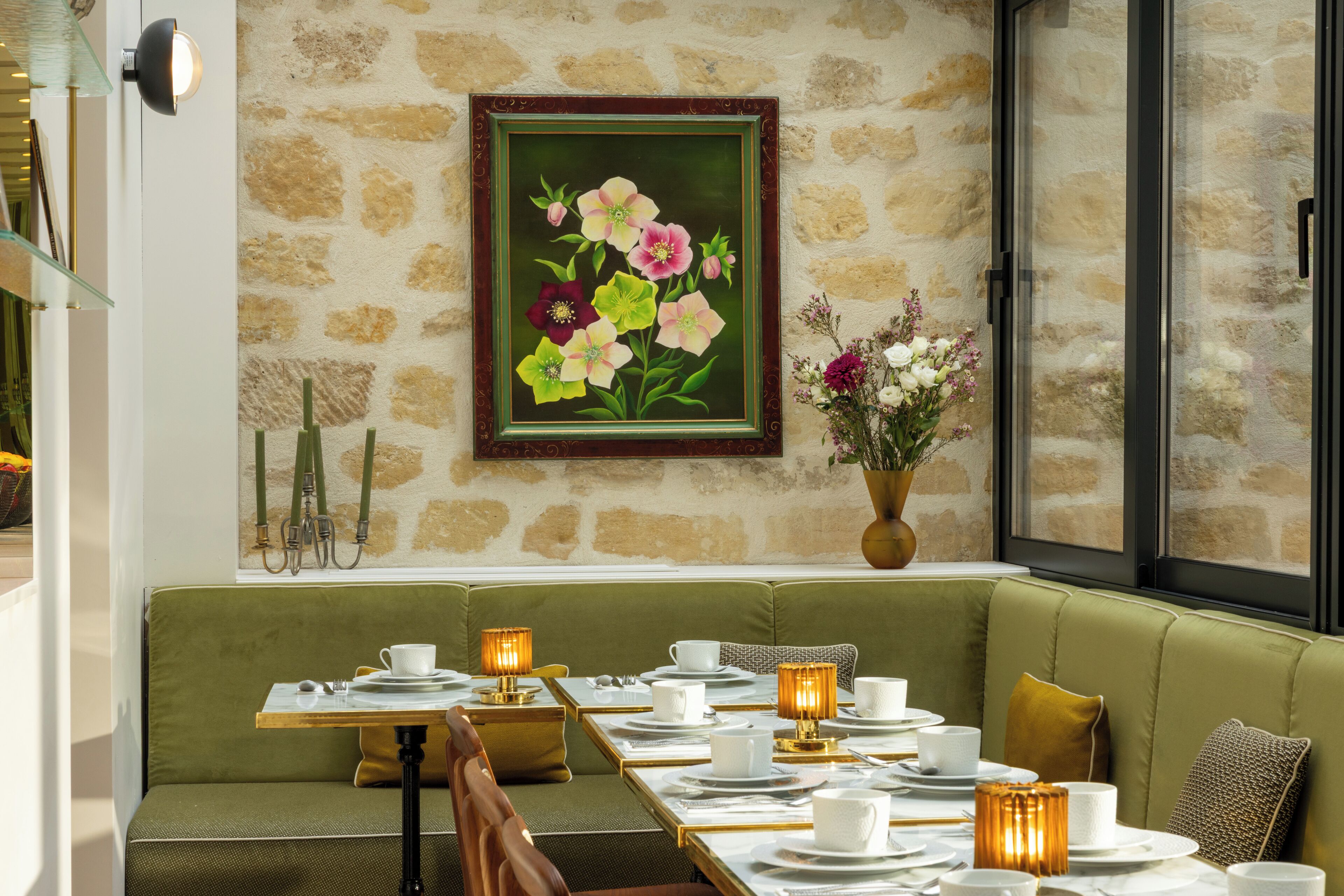 Un comedor con pared de piedra, un cuadro floral enmarco y un sofá verde.
