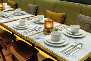 A dining area with a long table set for multiple guests, featuring white plates, cups, and silverware.