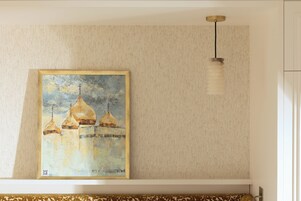 Een schilderij van koepelconstructies aan een muur, een hangende lamp en een gestreept sofa.
