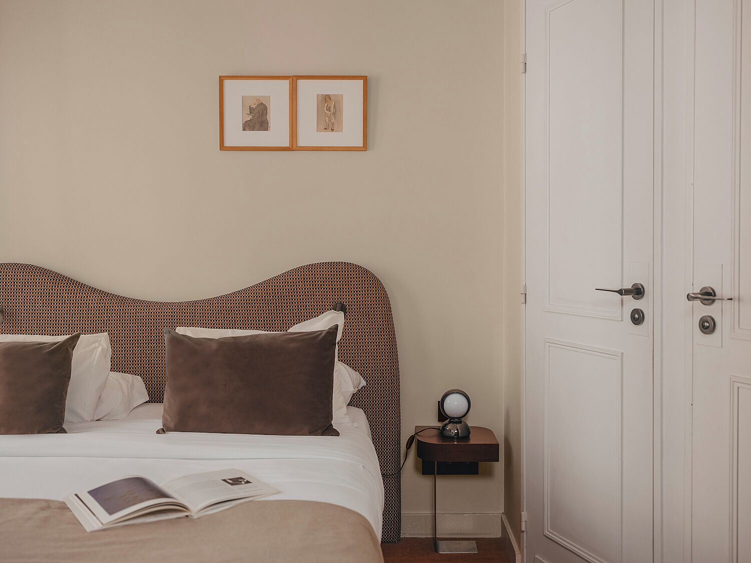 Una camera d'albergo ordinata con un letto, un comodino con una lampada e una porta.