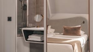 Una habitación de hotel moderna con una cama grande, un baño con ducha y un espejo.