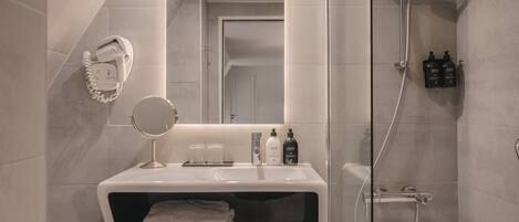 A modern bathroom with a vanity, a mirror, a shower, and a toilet.