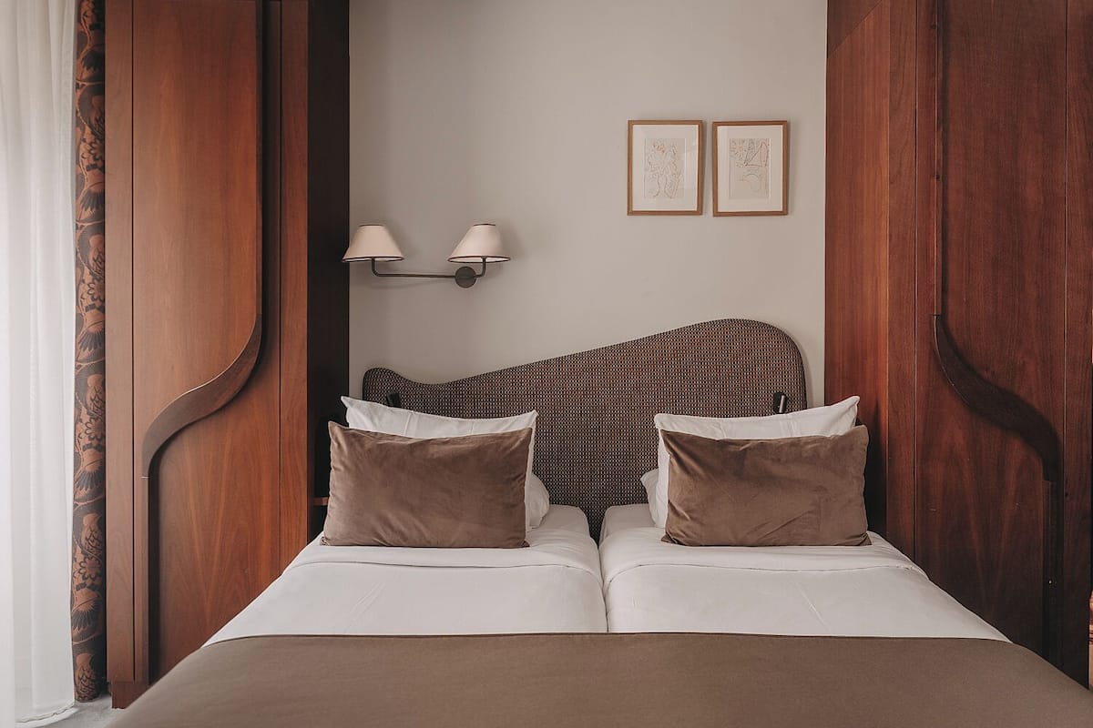 Habitación de hotel con una cama grande, dos lámparas fijadas a la pared y dos cuadros enmarcados.