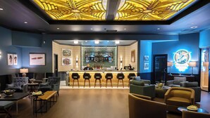 A bar area with a counter and bar stools, a seating area with armchairs and a sofa, and a ceiling with a decorative pattern. - Hollywood Casino Gulf Coast (Bay St Louis)