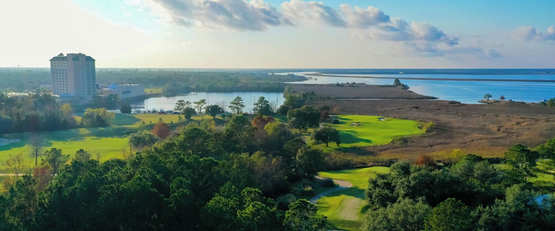 A golf course with a water body and a building in the background.