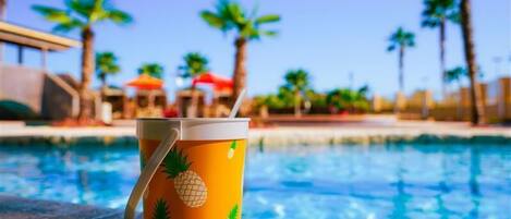 Un entorno junto a la piscina con un vaso con motivos de piña en un repisa.