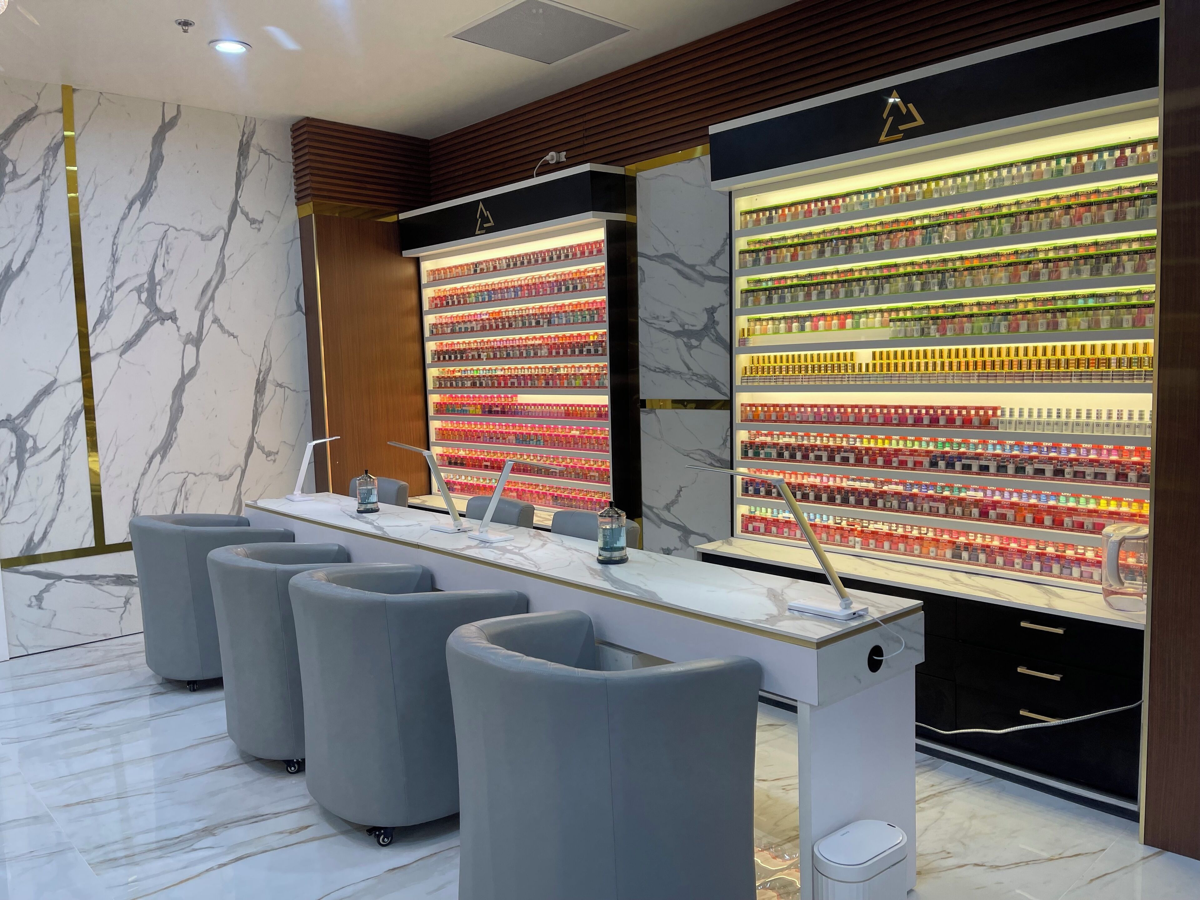 Un moderno espacio de spa con una pared de mármol, un mostrador de recepción y exhibición de diversos productos.