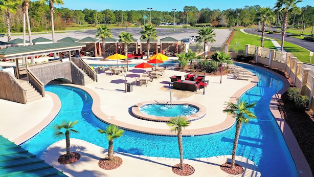 A swimming pool area with multiple lanes, palm trees, and lounge chairs. - Hollywood Casino Gulf Coast (Bay St Louis)