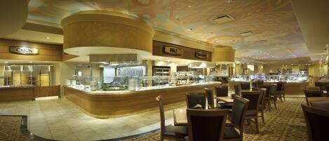 A restaurant area with a curved counter, multiple seating arrangements, and a ceiling with a floral design.