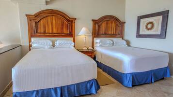 Una habitación de hotel con dos camas, una mesita de noche con lámpara y un cuadro enmarcado en la pared.