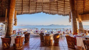 An outdoor dining area with tables and chairs, overlooking the sea. - Barceló Karmina All Inclusive (Manzanillo)