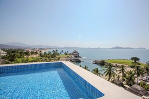 A swimming pool with a view of the ocean and mountains.