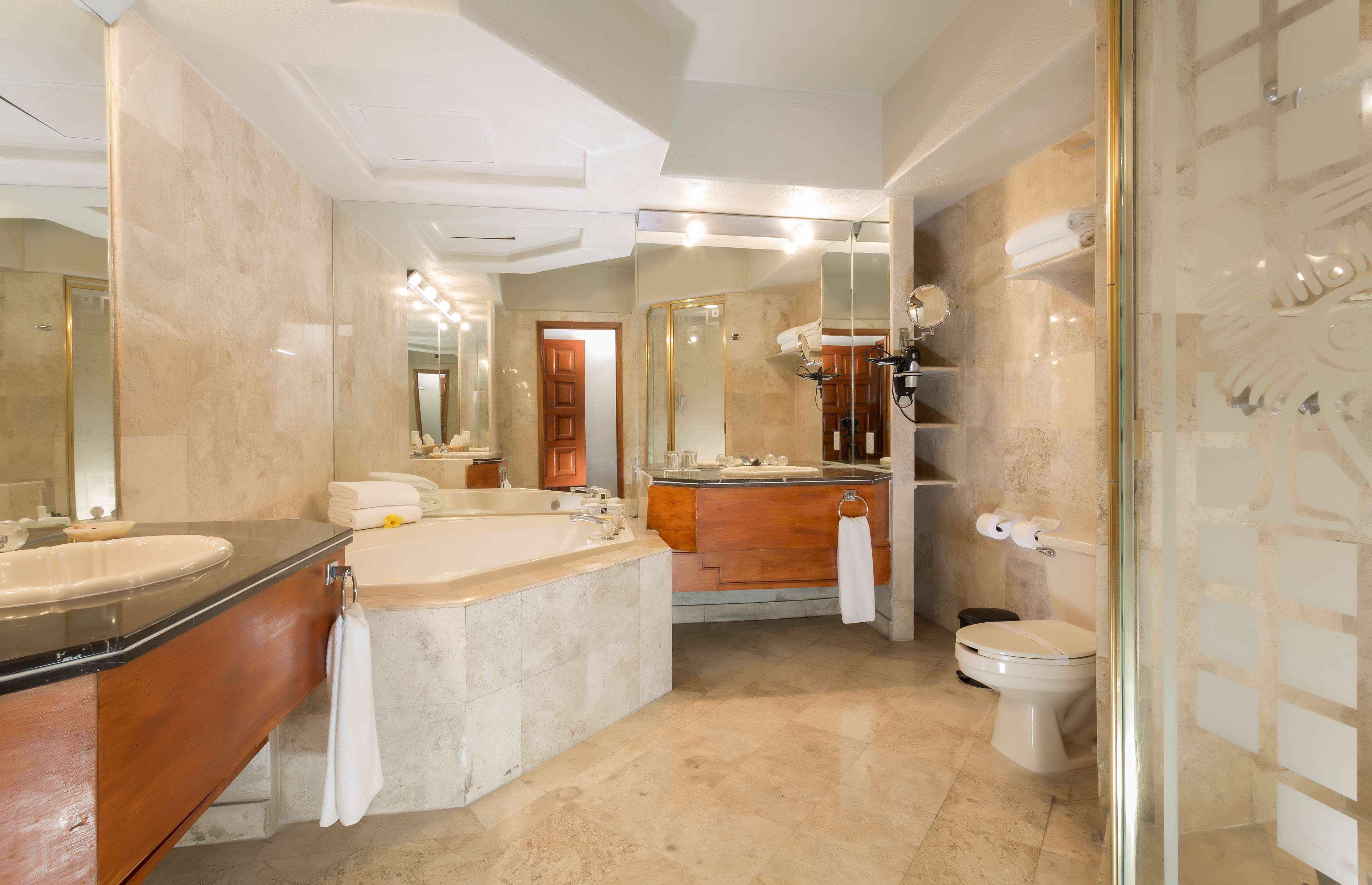 Een moderne badkamer met een ruim bad, een aparte douche en een toilet.