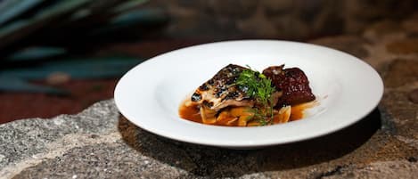 A white plate with a dish of food on a stone surface.