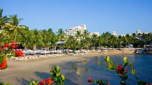 A beachfront hotel with palm trees, beach umbrellas, and lounge chairs. - Barceló Karmina All Inclusive (Manzanillo)