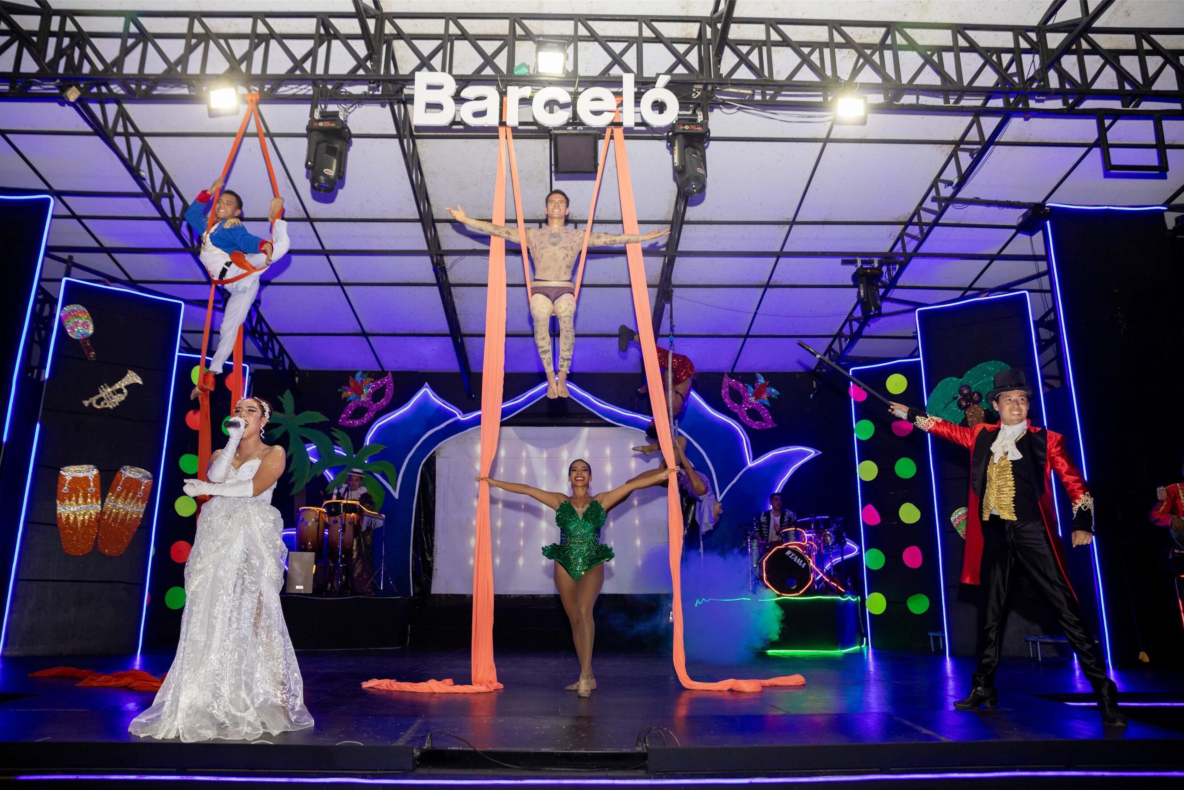 Un escenario con artistas, un soporte para micrófono y un letrero que dice 'Barceló'.