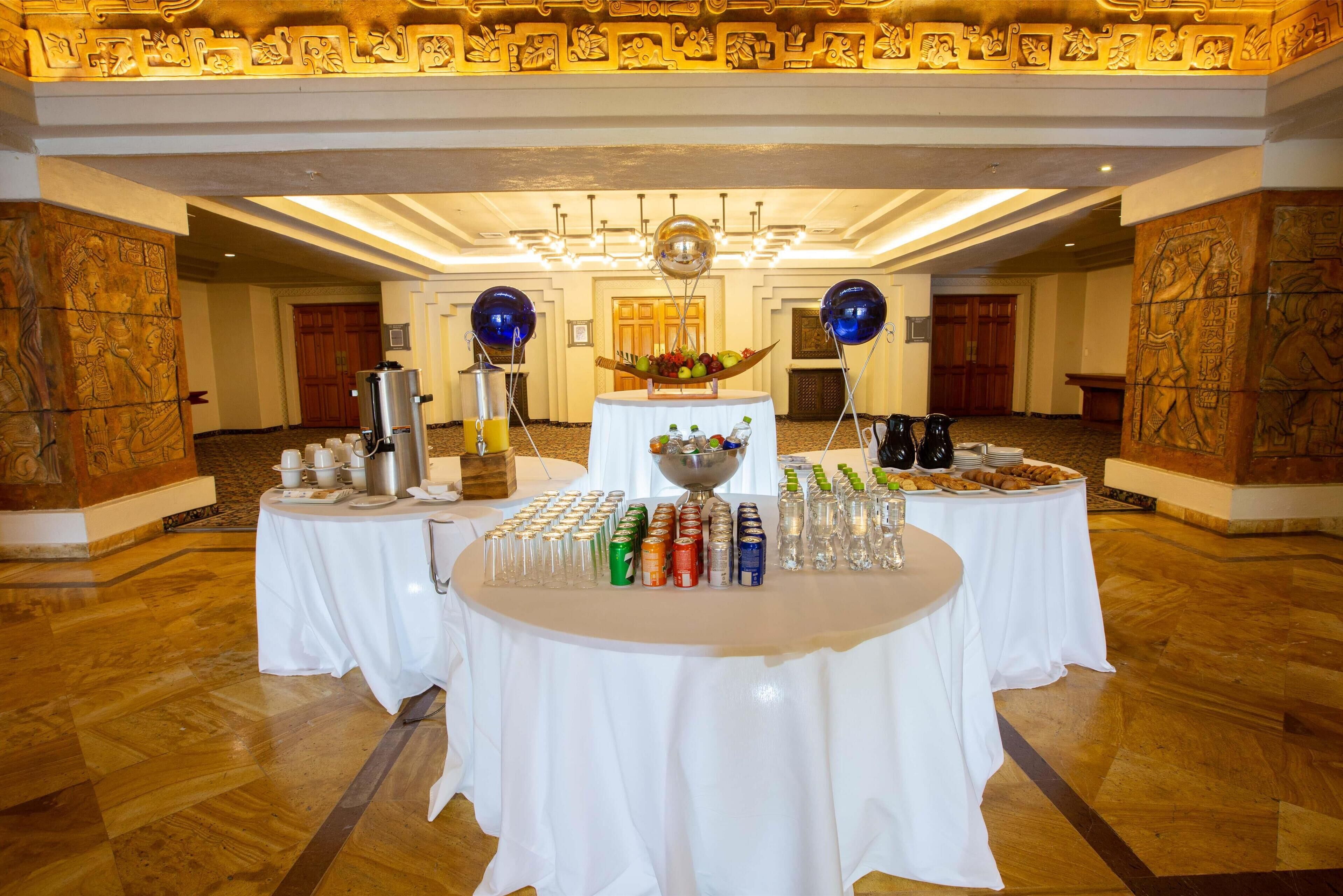 A banquet hall with tables set for a buffet, featuring a variety of food and drink options.