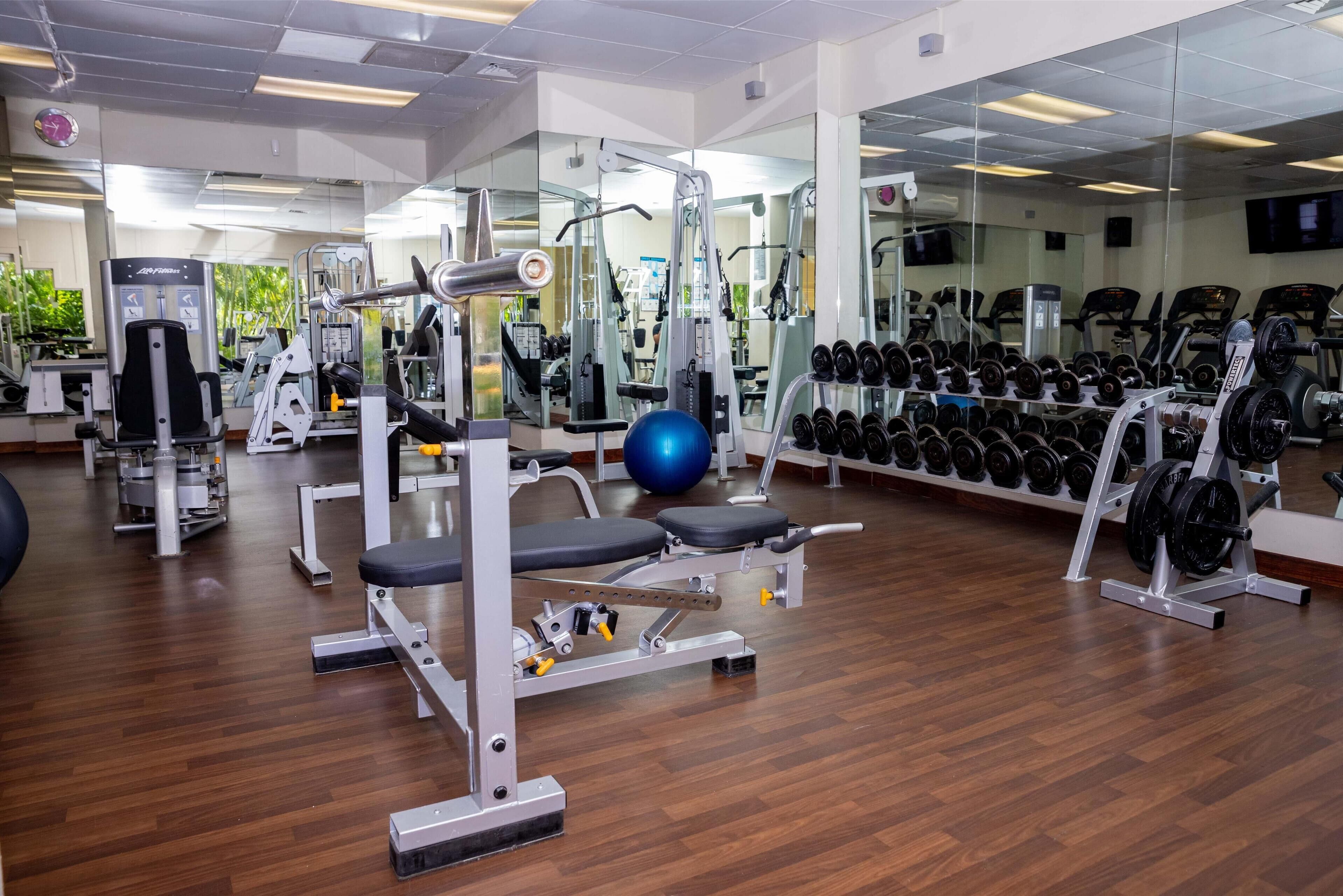 Une salle de sport équipée de divers appareils d’entraînement, notamment des machines de musculation, des haltères et des ballons d’exercice.