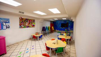 Un aula con sillas y mesas coloridas, y carteles educativos en las paredes.