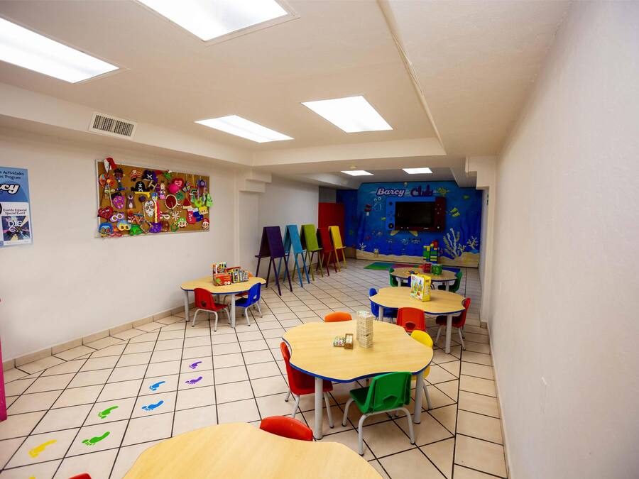 Un aula con sillas y mesas coloridas, y carteles educativos en las paredes.