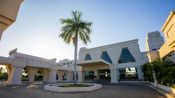 A modern building with a central atrium, palm trees, and a paved courtyard.