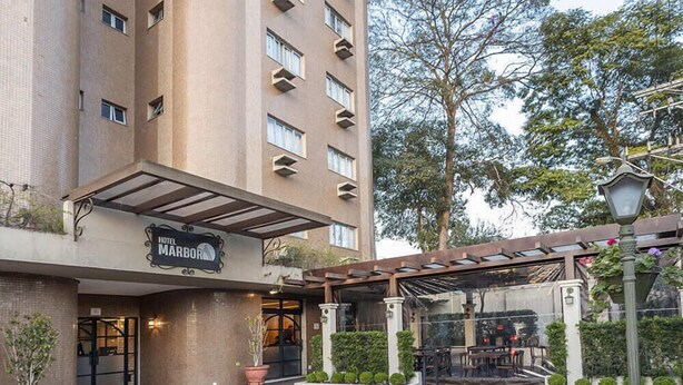 A hotel entrance with a covered outdoor seating area and a sign reading "Hotel Marbor." - Hotel Marbor (Mogi das Cruzes)