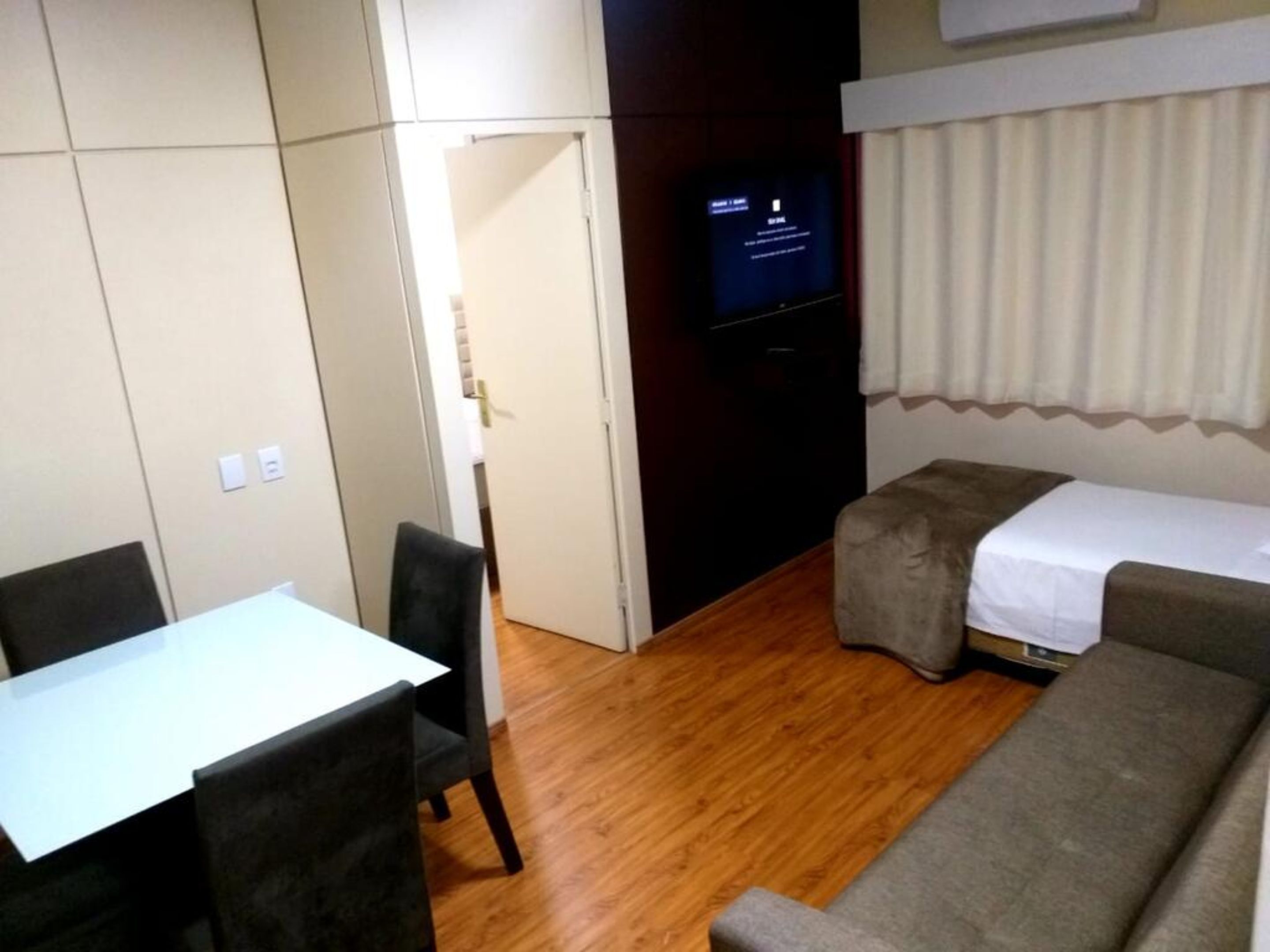 Una habitación pequeña con cama, una mesita y televisor.