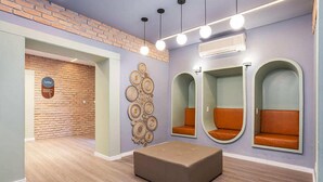 A room with a brick wall, a circular wall decoration, and three cushioned seating areas. - Hotel Marbor (Mogi das Cruzes)