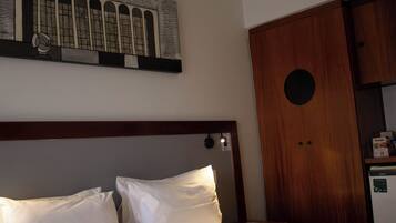 Una habitación de hotel con una cama, un armario de madera y una obra de arte colgada en la pared.