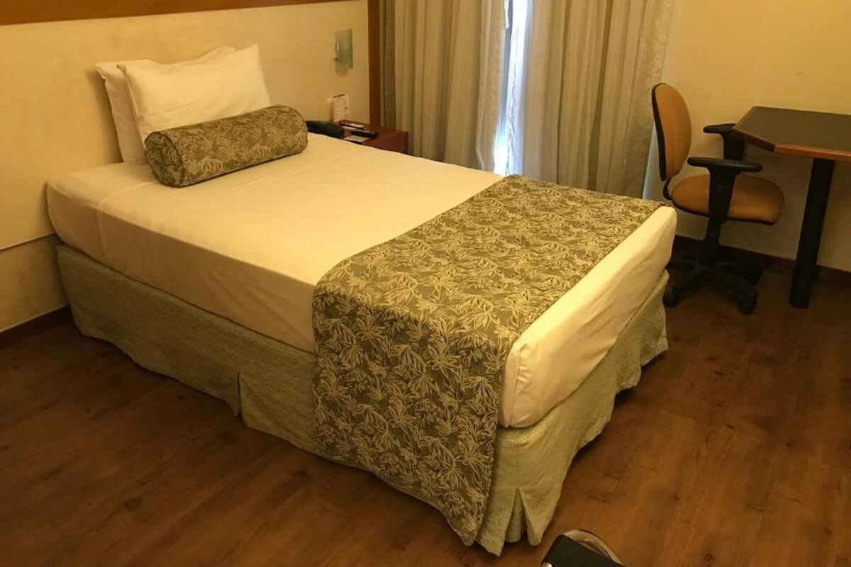 Una habitación de hotel con una cama, un escritorio y una silla.