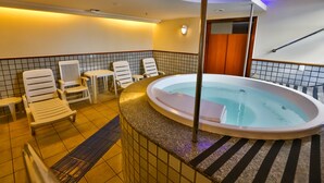 Un espace bien-être comprenant un jacuzzi, des chaises longues et un sol carrelé.