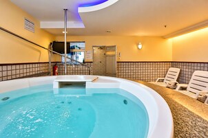 Un jacuzzi con un muro de azulejos e iluminación azul en el techo.