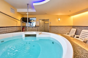 Un bain à remous avec un mur carrelé et un plafond éclairé d’une lumière bleue.