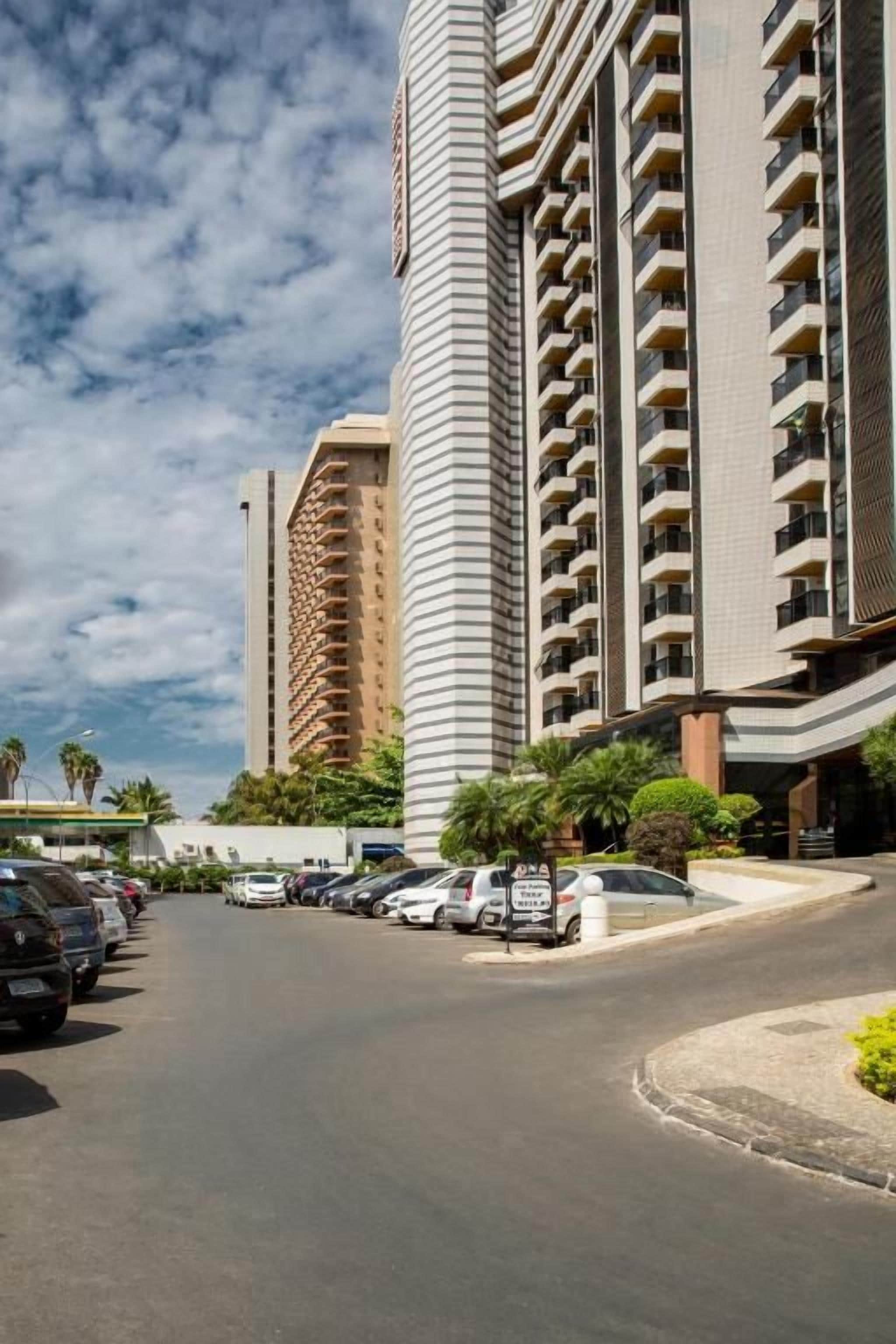 A multi-story hotel with a curved driveway and parked cars.