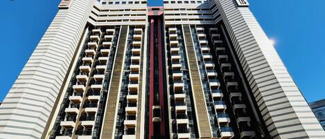 Un edificio alto con molti balconi e un elemento verticale centrale.