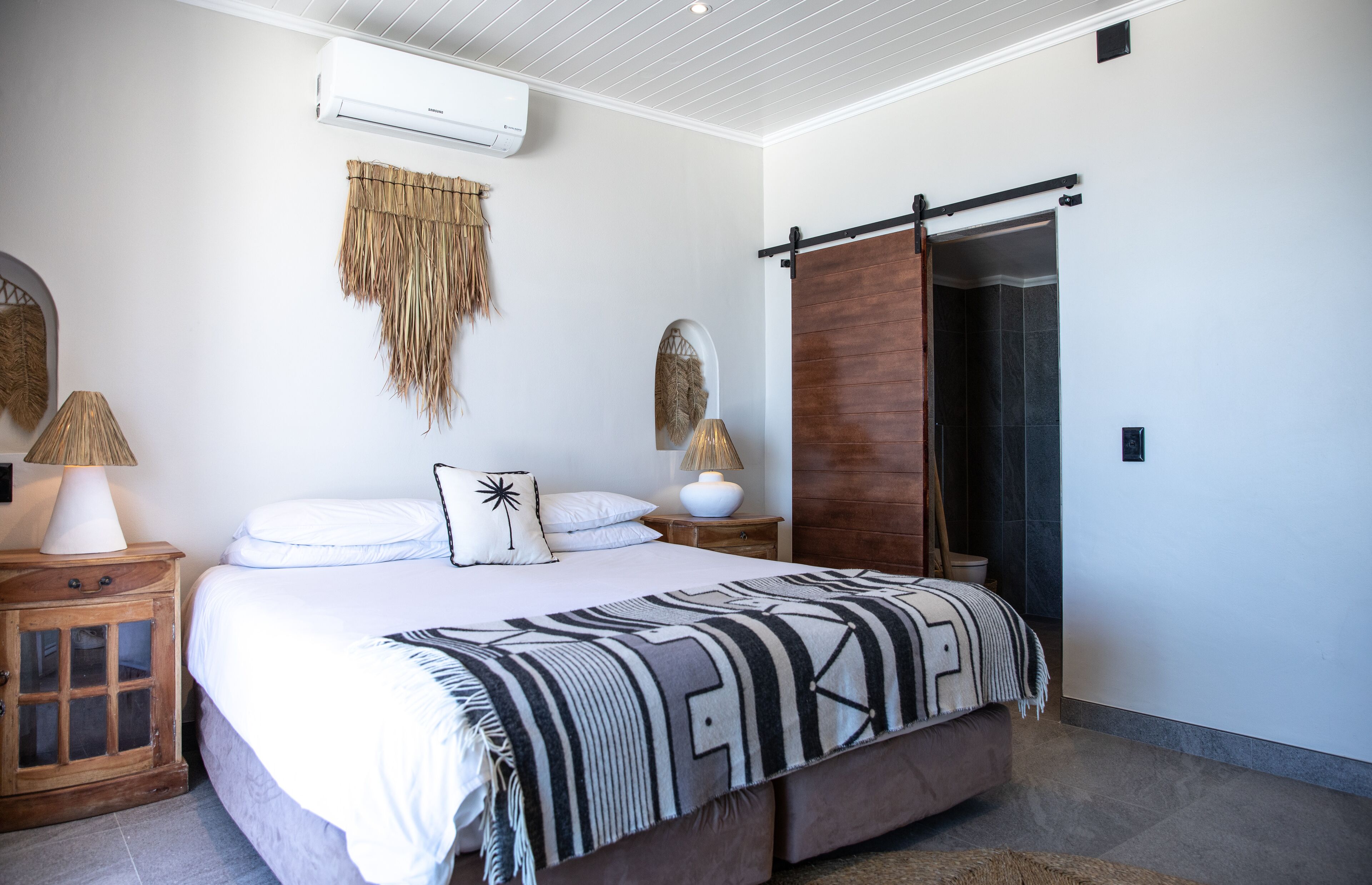 A bedroom with a bed, a nightstand, a wardrobe, and a wall-mounted air conditioner.