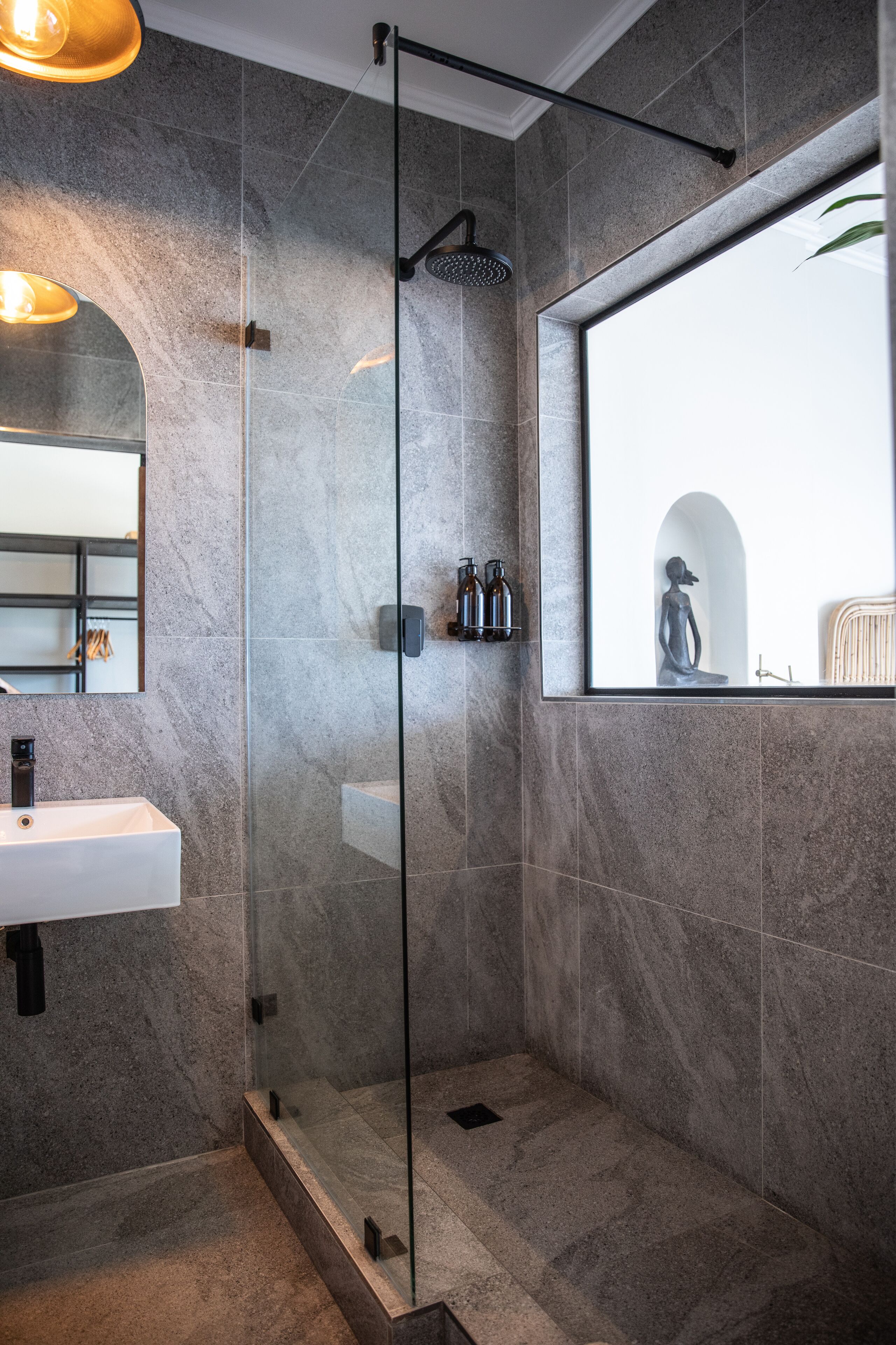 A modern bathroom with a glass-enclosed shower, a white sink, and a large mirror.