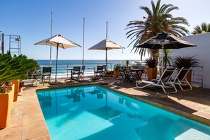 Een buitenzwembad, parasols voor strand/zwembad