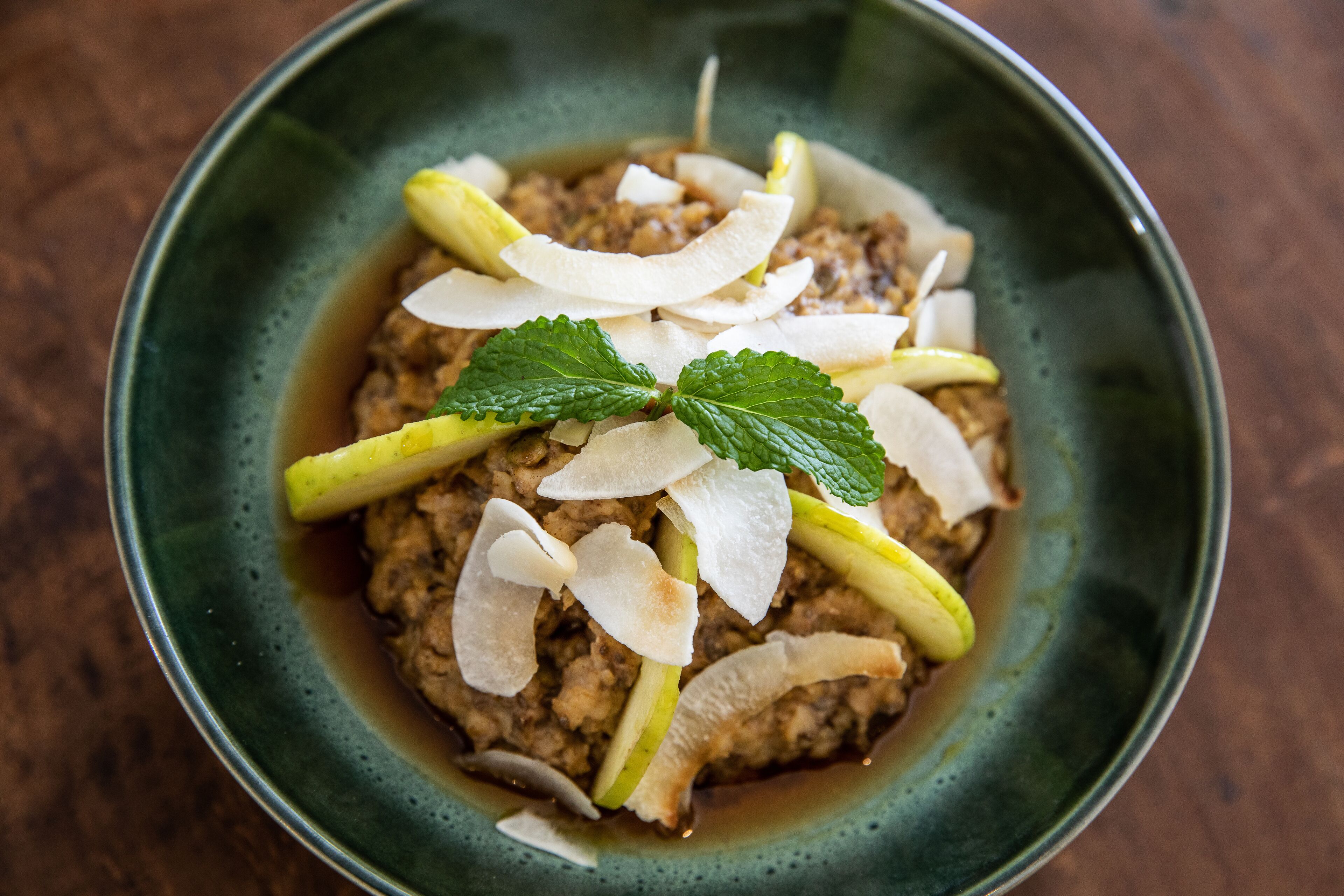 A bowl of food with a green bowl and a wooden table.